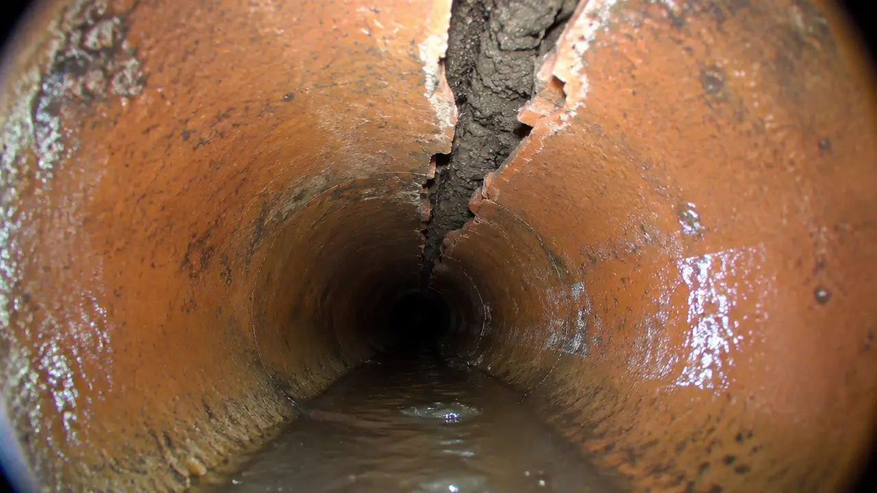 Sewer camera view of a long crack along the top of a clay pipe